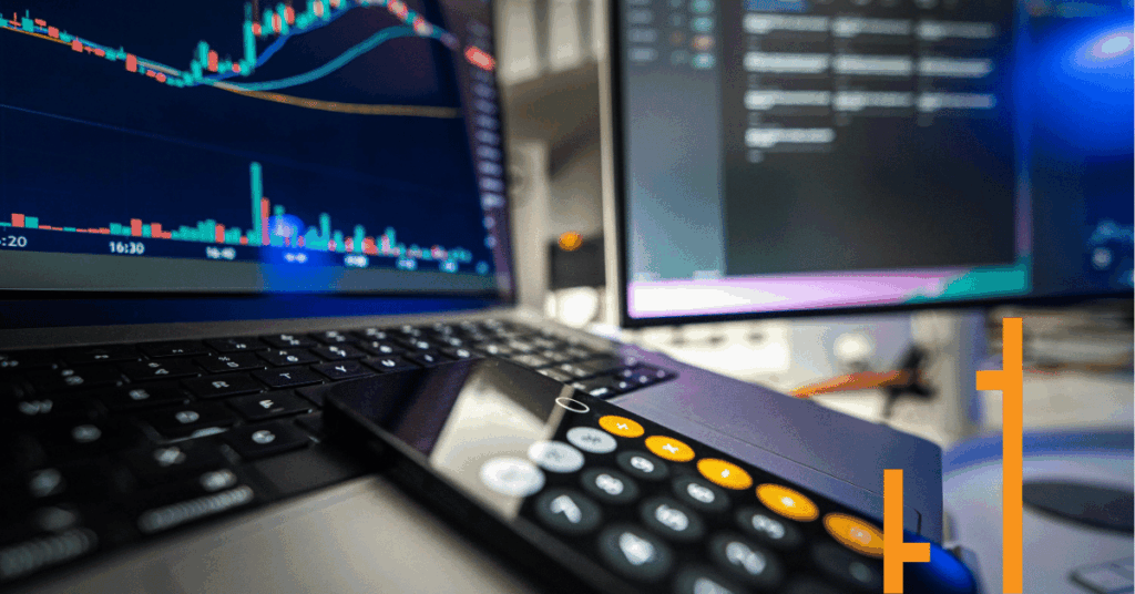 Stock market chart on laptop with calculator and trading screens.