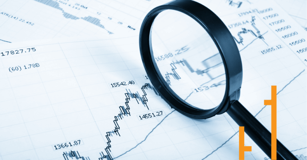 Magnifying glass over stock market charts and candlestick patterns representing The Chartist’s expert market analysis and trading insights.